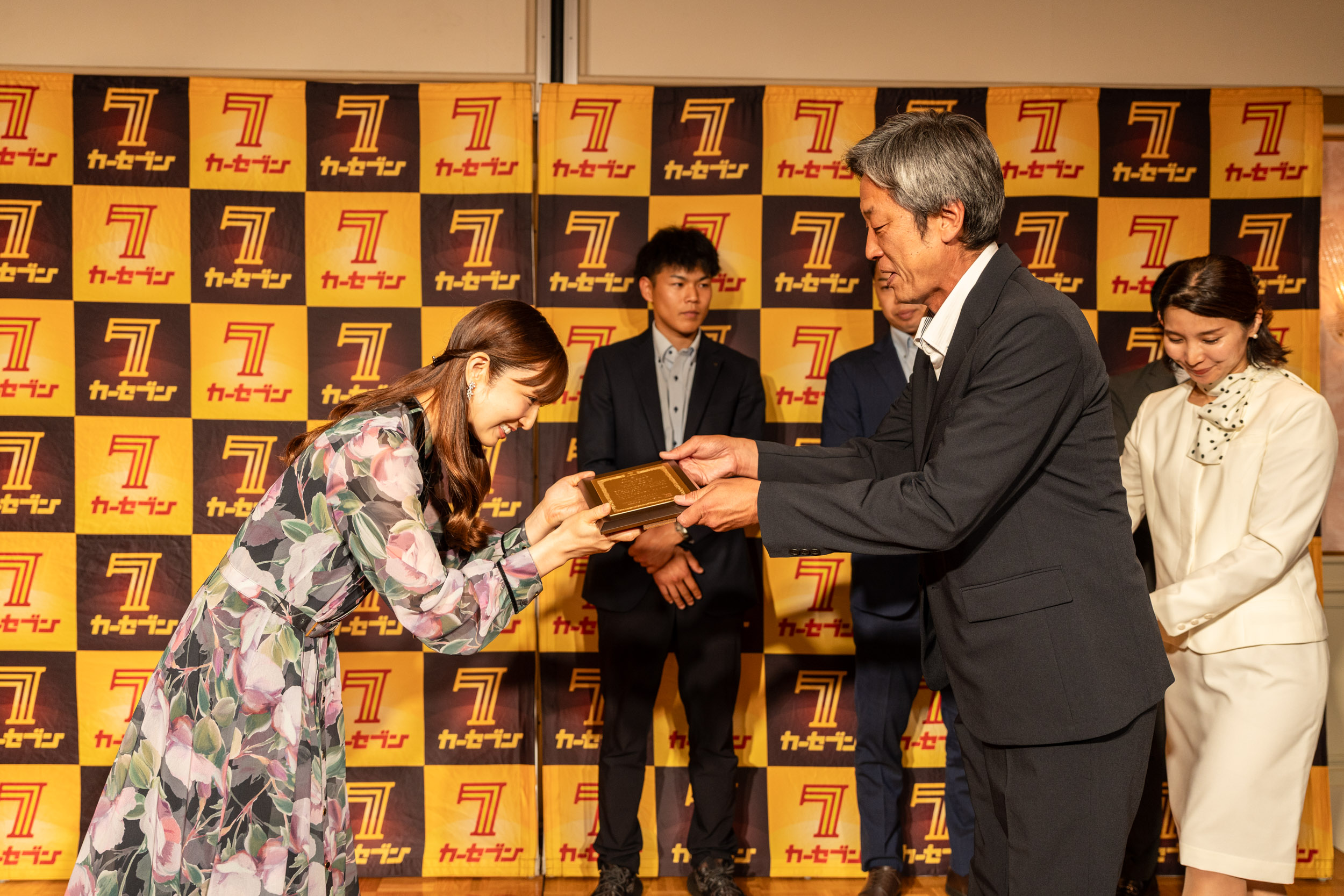 全国スタッフ会議での優秀店舗表彰の様子。小倉優子さんから優秀店舗スタッフへ記念の盾が手渡されている